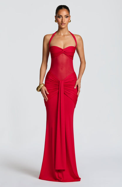 Model wearing a red slinky maxi dress with a sweetheart twist bust, halter ties and sheer mesh midriff
